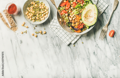 Vegan lunch bowl. Flat-lay of dinner with avocado, mixed grains, beans, sprouts, greens and vegetables over marble background, top view, copy space. Clean eating, vegetarian, diet food concept