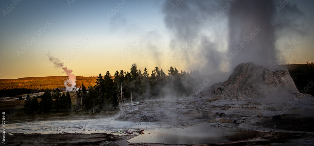 Castle and Old Faithful Geysirs erupting at twilight