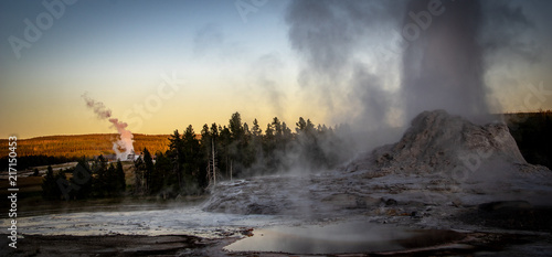 Castle and Old Faithful Geysirs erupting at twilight