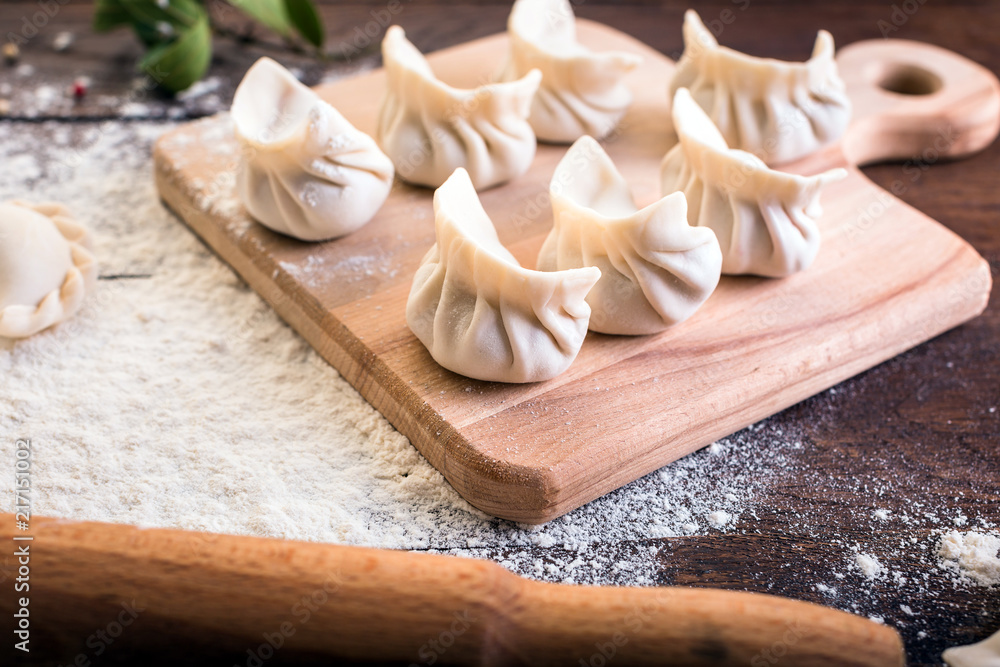 Pelmeni cooking on a board and wooden background, national Russian cuisine, vareniki Pelmeni cooking on a board and wooden background, national Russian cuisine, vareniki