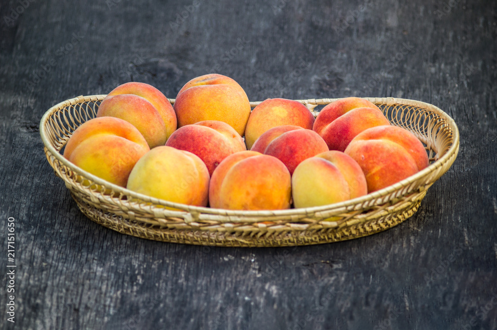 Fresh peaches in wicker basket on dark wood background Fresh peaches in wicker basket on dark wood background