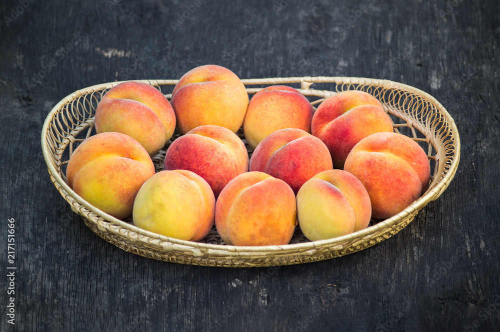 Fresh peaches in wicker basket on dark wood background Fresh peaches in wicker basket on dark wood background