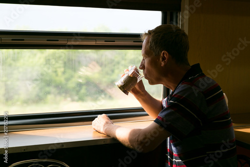 A man is riding in a train restauran. A man 40 - 50 years old is drinking tea in a long-distance train.