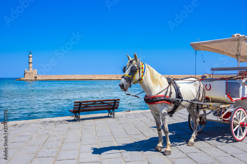 Horse carriages and lighthouse at the old harbor of Chania, Crete, Greece.