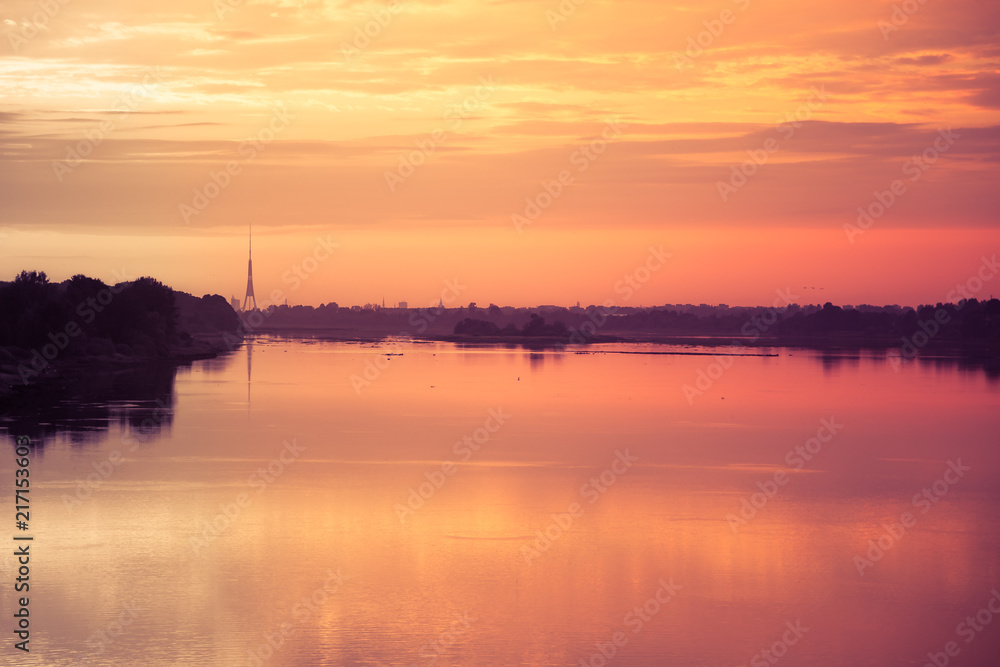 Bright, colorful evening landscape over the river Daugava of pink and purple tones. Dramatic sunset scenery in Latvia, Northern Europe.