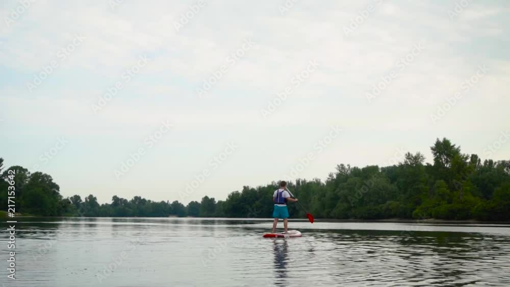 Handsome guy swims standing on a kayak Handsome guy swims standing on a kayak