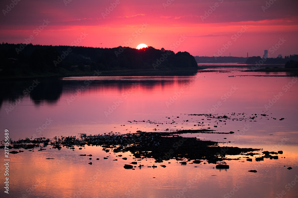 Bright, colorful evening landscape over the river Daugava of pink and purple tones. Dramatic sunset scenery in Latvia, Northern Europe.