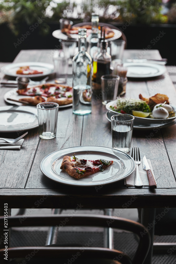 tasty pizza and salad on table at modern restaurant
