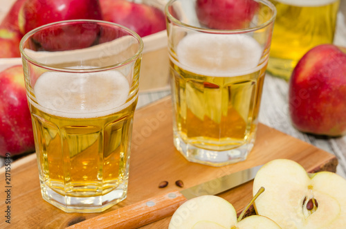 Apple cider and a basket with fresh apples on rustic wooden background 