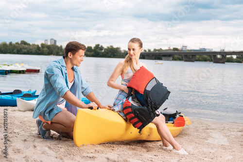 About kayaking. Caring blonde-haired husband wearing blue shirt telling his woman about kayaking