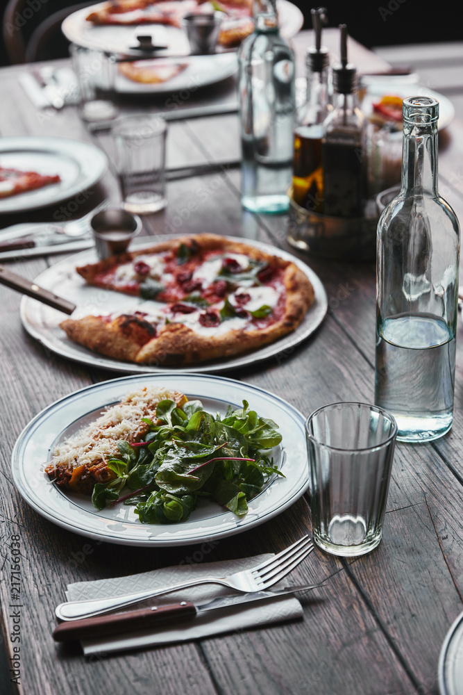 close-up shot of delicious pizza and lasagne on wooden table with water close-up shot of delicious pizza and lasagne on wooden table with water