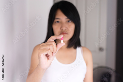 Woman with pills or capsules on hand and feeling bored