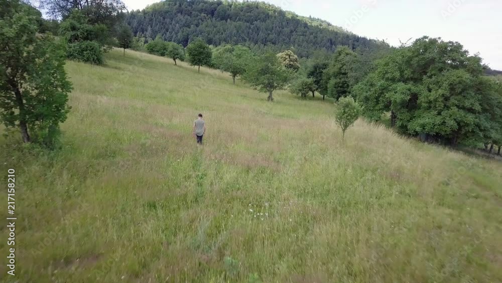 A young man is walking over a field in slow motion. His facial expression looks very thoughtful. A young man is walking over a field in slow motion. His facial expression looks very thoughtful.