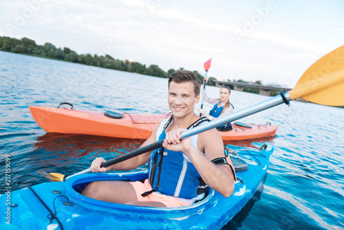 Summer date. Blonde-haired man smiling broadly while having nice summer date kayaking in the river © Viacheslav Yakobchuk