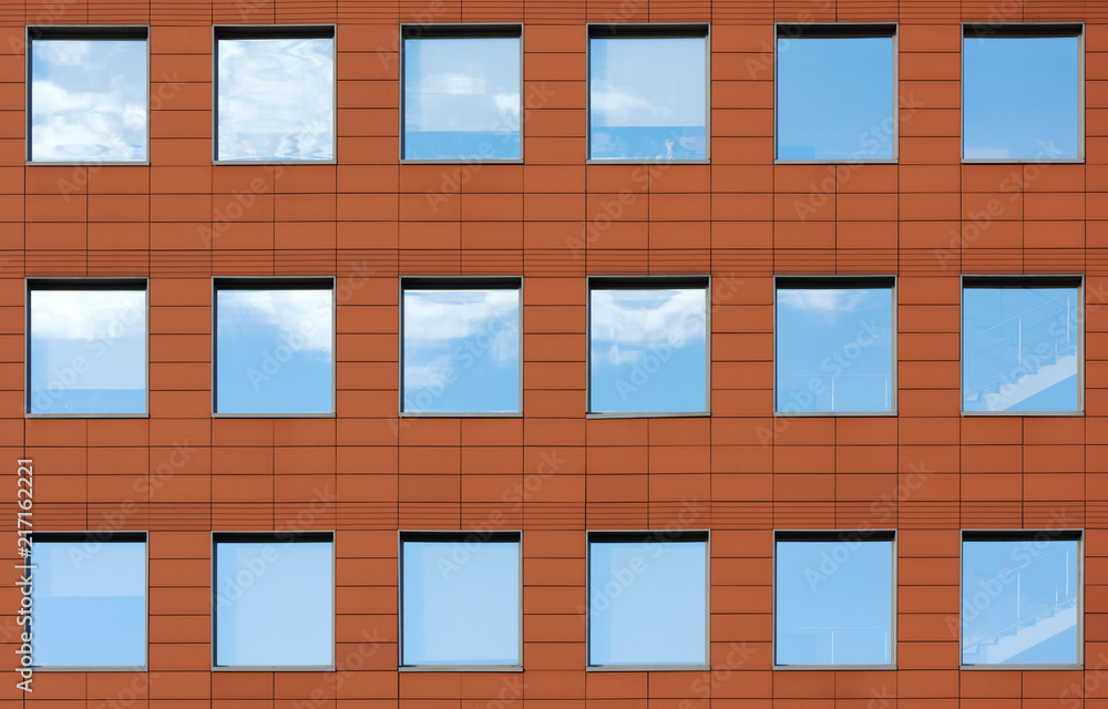 Minimalist facade of modern office building with square Windows. Finish is a dark red color Minimalist facade of modern office building with square Windows. Finish is a dark red color