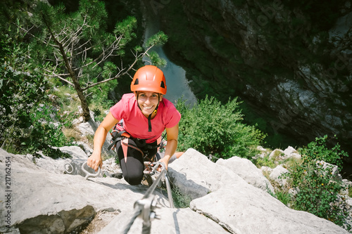 Young happy woman who is climbing along a via ferrata 