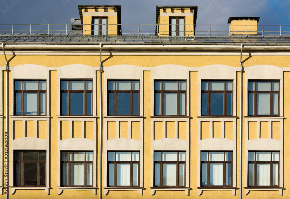 The facade of the old building with yellow walls and white décor on the windows The facade of the old building with yellow walls and white décor on the windows