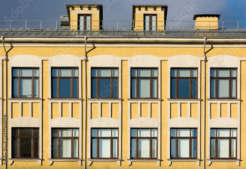 The facade of the old building with yellow walls and white décor on the windows