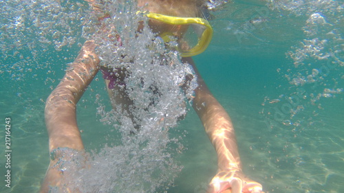 Portrait of little girl swimming underwater in sea. Cute girl in mask creates bubbles under water.Summer vacation. Small girl has fun. Copy space photo