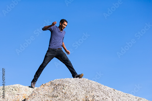 Young Man Taking Large Step Across  Boulders