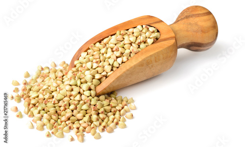 uncooked buckwheat in the wooden scoop, isolated on the white background.