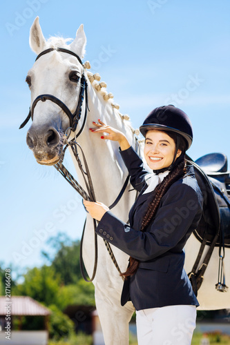 Fond of equestrianism. Beautiful smiling businesswoman fond of equestrianism coming to race track