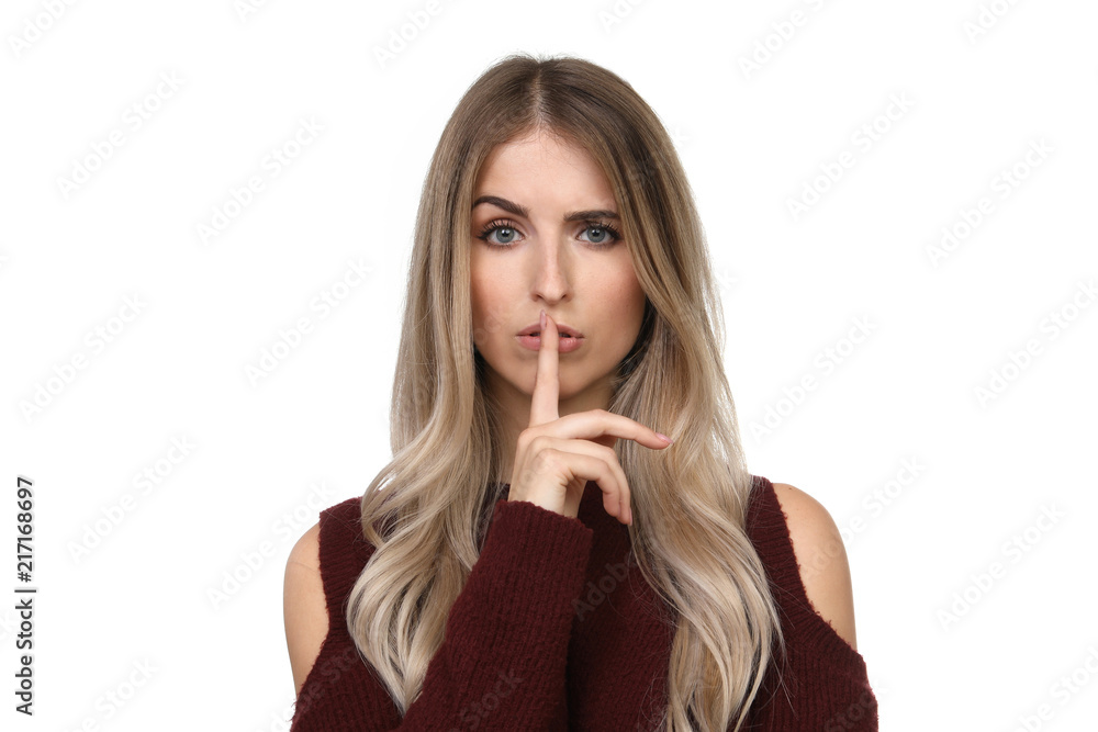 Hübsche blonde Frau legt sich einen Finger auf die Lippen und zeiht eine Augenbraue hoch Hübsche blonde Frau legt sich einen Finger auf die Lippen und zeiht eine Augenbraue hoch