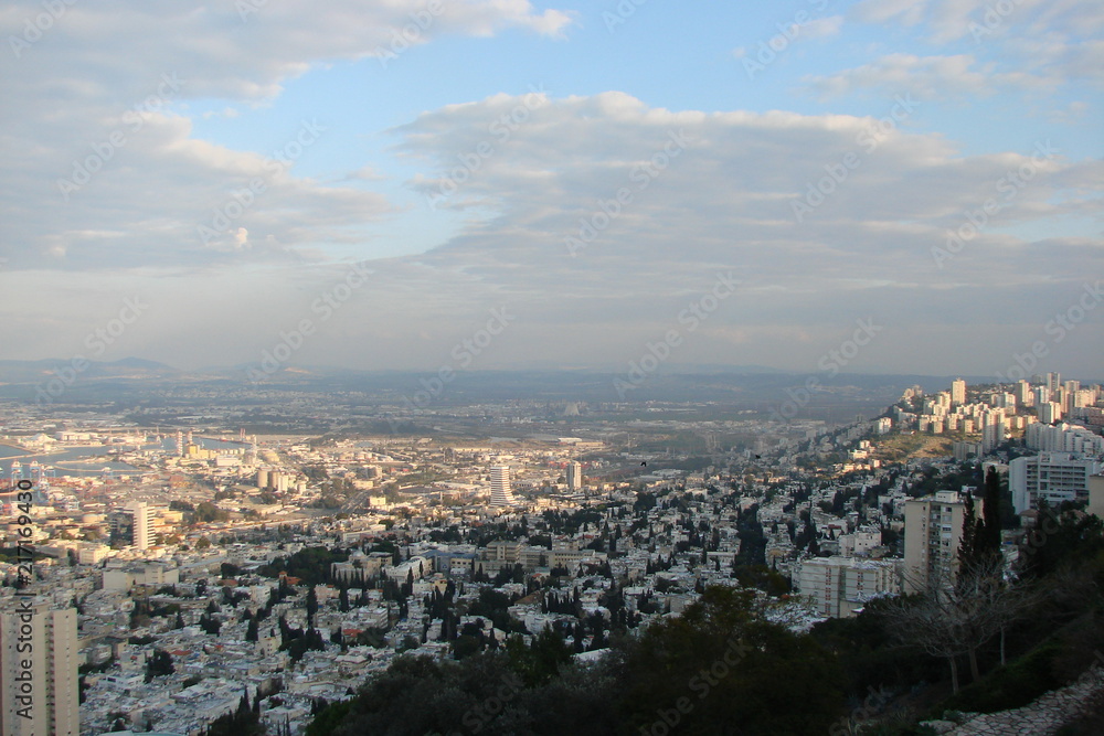 Panorama of various colors of cloudy blue sky in the sunset over the streets and parks of Haifa.
