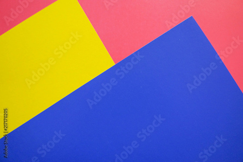 Modern flat lay background with color paper sheets. Yellow, blue and pink.