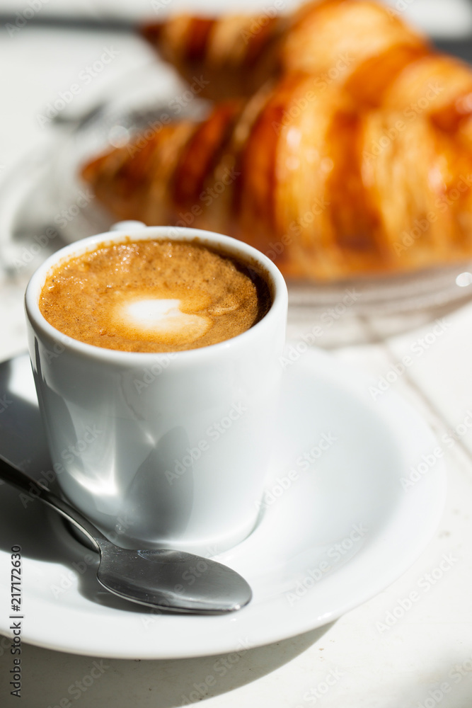 Hot coffee and croissant breakfast in a sunny morning, natural light.