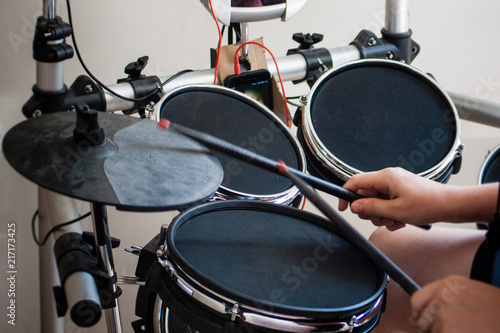 unrecognized boy playing electronic drums with black drumsticks