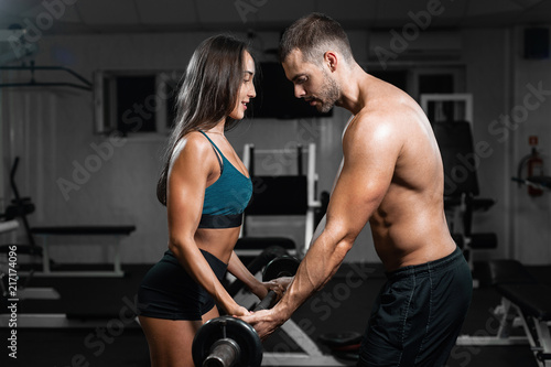 Man instructor and woman train, lifting dumbbells