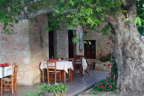 Stühle und Tische einer Taverne unter einer Platane