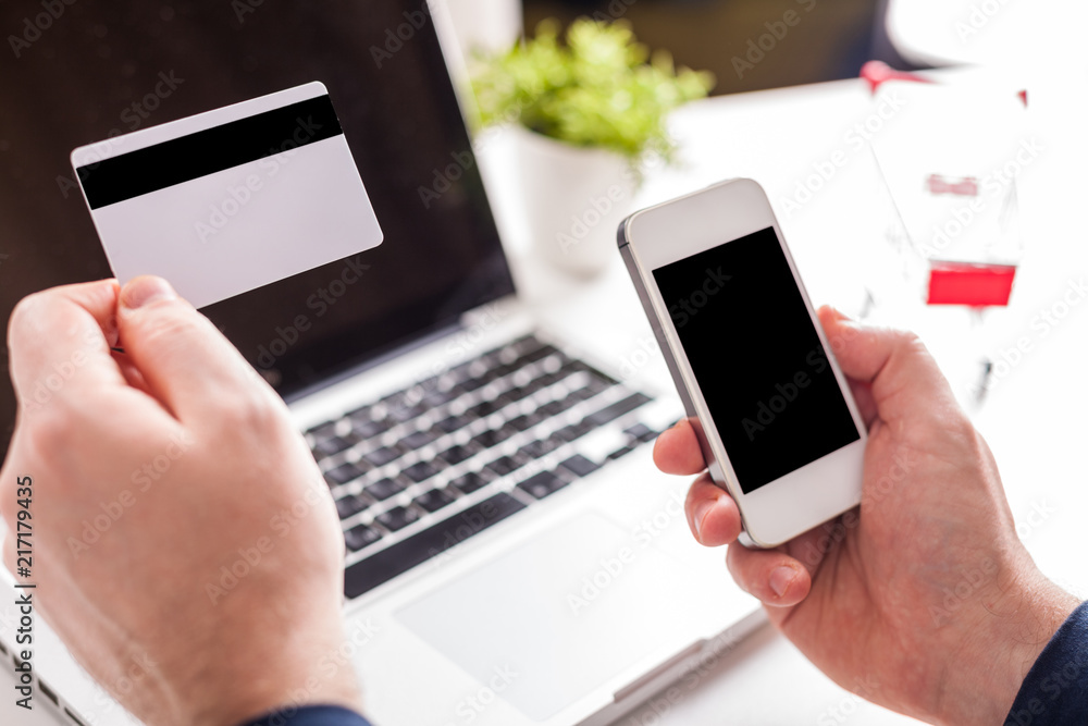 A man is going to pay for the goods in the internet using credit card and laptop computer. Online shopping concept. A man is going to pay for the goods in the internet using credit card and laptop computer. Online shopping concept.