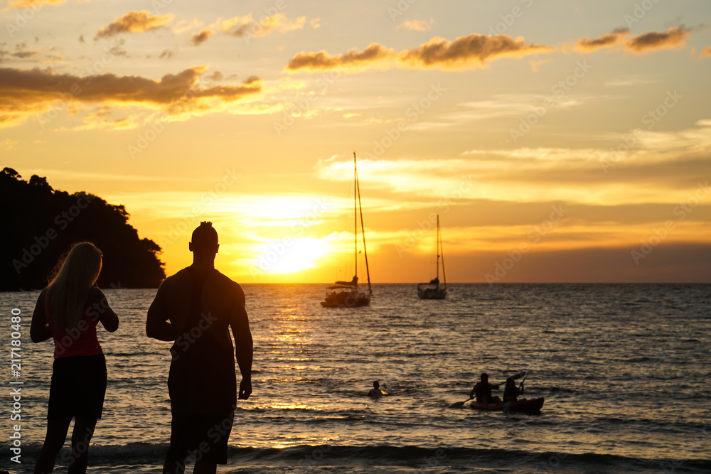 Fototapeta premium a couple stand watch sunset take photo by the beach