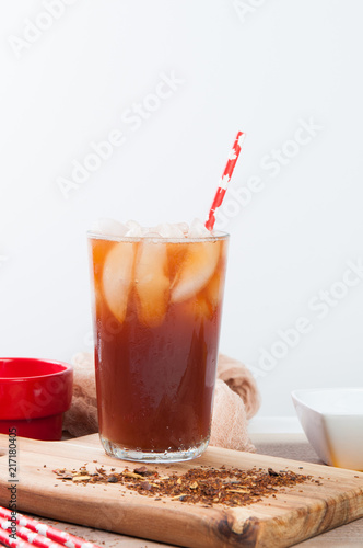 Glass of iced tea with ice cubes and a paper straw