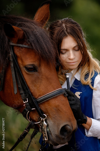 Young woman rider hugging with brown horse, eyes closed. Concept friends