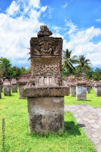 Photo of old stone monument with carvings of patterns and small person in Waruga in Airmadidi, North Sulawesi, Indonesia. photo