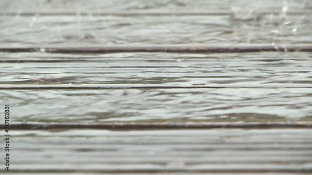 Hand-held, close-up of heavy rain falling on porch decking Hand-held, close-up of heavy rain falling on porch decking