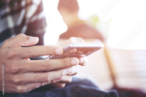 Young business man two plaid shirt using on cell phone sit and waiting flight during rest in airport. sitting sofa in watching message on mobile phone during break.