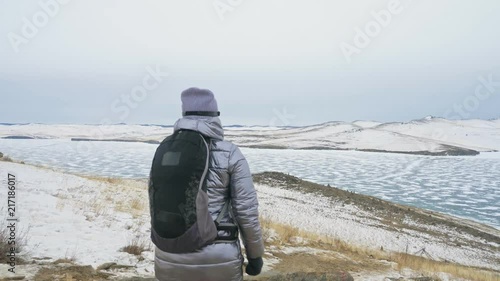 Travel of woman on ice of Lake Baikal. Close unique buddhist stupa burkhan monument symbol mystical historic ritual island Ogoi landscape mountains shamanic worship. Trip to winter island. Hiker wears photo