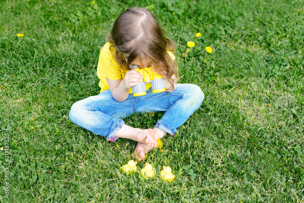 cute little girl playing with rubber duck and plastic binoculars outdoors. beautiful baby having fun with a toy duckling. home development of children. selective focus. cute little girl playing with rubber duck and plastic binoculars outdoors. beautiful baby having fun with a toy duckling. home development of children. selective focus.