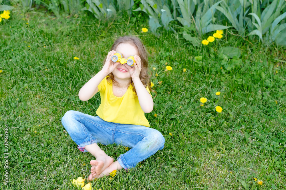 Fototapeta premium cute little girl playing with rubber duck and plastic binoculars outdoors. beautiful baby having fun with a toy duckling. home development of children. selective focus. 