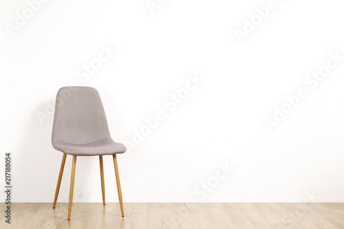 Fototapeta Naklejka Na Ścianę i Meble -  Single elegant gray loft style chair standing alone on wooden floor in empty room, big blank wall background. Large copy space for text. Only one vacant seat. Human resources hiring campaign concept.