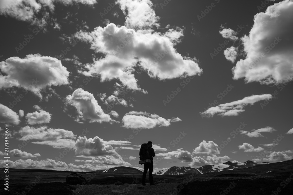 Hiker standing below dramatic clouds