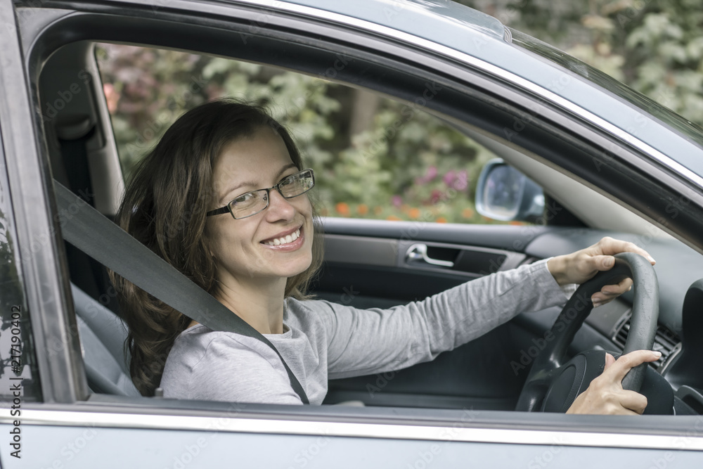 Happy young woman driver sits in car. 