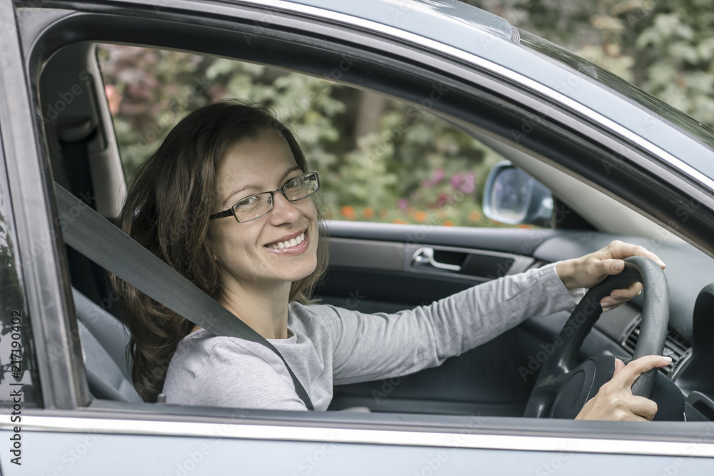 Happy young woman driver sits in car. Happy young woman driver sits in car.