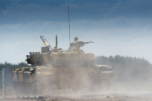 Military or army tank ready to attack and moving over a deserted battle field terrain. a lot of dust.