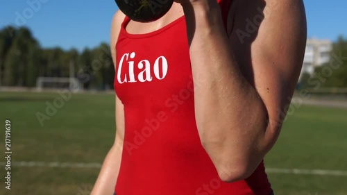 Camera Moves Around Fitness Girl Wearing Red Swimsuit and Jeans Shorts Training Arms With Dumbbells During Outdoors Workout photo