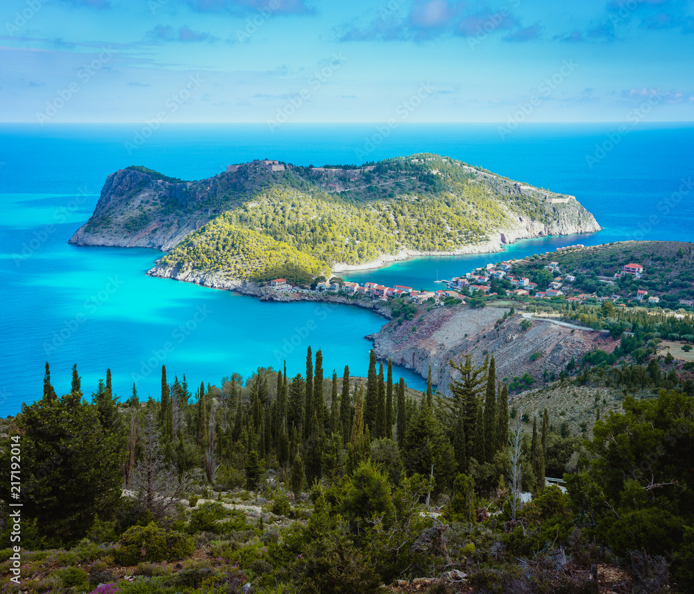 View to Assos village and beautiful blue sea. Cypress trees in foreground. Kefalonia island, Greece